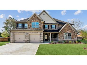 Inviting two-story home featuring a brick facade, manicured lawn, and a spacious three-car garage at 1301 Odell Ct, Hoschton, GA 30548