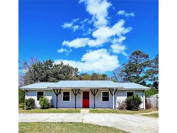 Charming single-story home with a well-maintained yard, metal roof, and a bright red front door at 1320 Milstead Ne Ave, Conyers, GA 30012