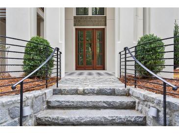 Stone steps lead to a welcoming front entrance with a black iron railing and symmetrical landscaping at 98 Sheridan Dr, Atlanta, GA 30305