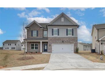 Two story home featuring a two car garage, brick accents, gray siding, and blue shutters at 704 Bristol Dr, Loganville, GA 30052
