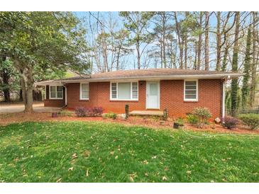 Charming brick home featuring a well-maintained lawn and mature trees at 1334 Jennie Sw Ln, Lilburn, GA 30047