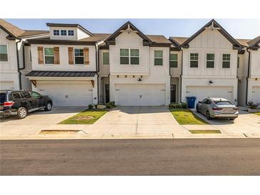 Charming townhomes featuring a white brick facade, two stories, and individual one-car garages at 228 Auburn Valley Way, Auburn, GA 30011