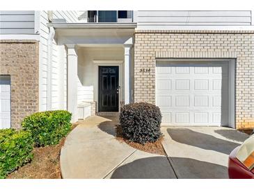 Charming townhome entrance with a black door, white trim, brick accents and an attached garage at 5634 Union Pointe Dr, Union City, GA 30291