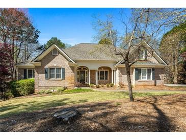 Charming single-story brick home with a manicured lawn and inviting front porch with white columns at 2504 Loch View Sw Ct, Conyers, GA 30094