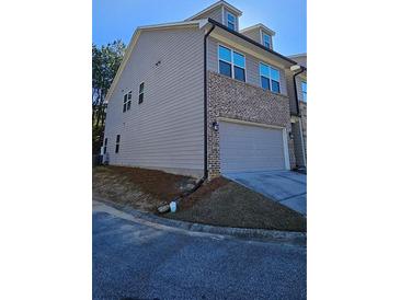 View of the home's side and front featuring a two-car garage and low-maintenance landscaping at 3285 Wild Basil Ln, Buford, GA 30519