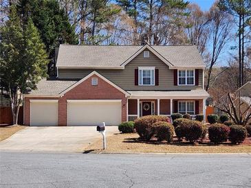 Charming two-story home featuring a three-car garage, landscaped yard, and inviting front porch with decorative wreath at 2702 Brookefield Nw Ln, Kennesaw, GA 30152