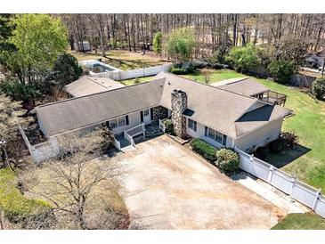 Charming home featuring a stone chimney, light colored siding, and a large concrete driveway at 115 Heritage Cir, Mcdonough, GA 30253