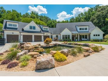 Stunning farmhouse exterior showcasing a tranquil rock pond and manicured landscaping at 201 Edwards Brook Ct, Canton, GA 30115