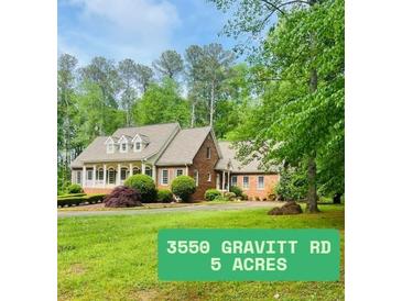 Charming brick home on five acres, featuring a manicured lawn and mature trees at 3550 Gravitt Rd, Cumming, GA 30040