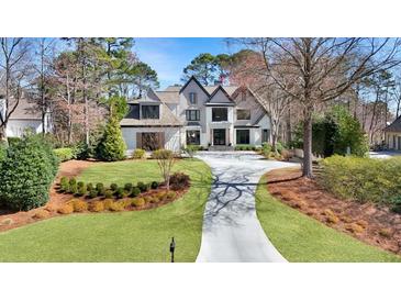 Stunning two-story home featuring a manicured lawn, lush landscaping, and a long driveway, all surrounded by mature trees at 1025 Abingdon Ln, Johns Creek, GA 30022