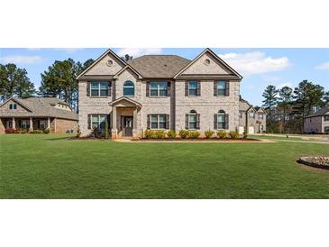 Stately brick two-story home featuring a manicured lawn and beautiful architectural details at 701 Cupcake Ct, Mcdonough, GA 30252