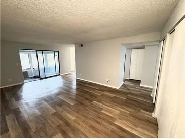 Open living room featuring wood-look flooring and a sliding glass door to a sunroom at 925 Seasons Pkwy, Norcross, GA 30093