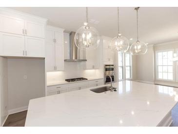 Bright kitchen features an island with pendant lighting, modern appliances, and sleek white cabinetry at 161 Basil St, Cumming, GA 30040