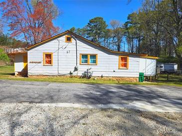Charming one-story home with a white exterior, orange trim, and a neatly maintained front yard at 2958 Klondike Rd, Lithonia, GA 30038