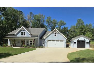 Charming light-blue farmhouse with a well-manicured lawn, concrete driveway, and a detached garage at 2317 Pleasant Grove Rd, Temple, GA 30179