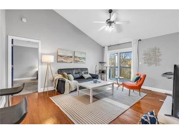 Bright living room with hardwood floors, vaulted ceilings, and access to a private balcony at 8303 Santa Fe Pkwy, Atlanta, GA 30350