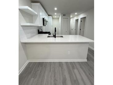 Bright kitchen with a quartz countertop island, stainless steel appliances and gray laminate flooring at 596 Windchase Ln, Stone Mountain, GA 30083