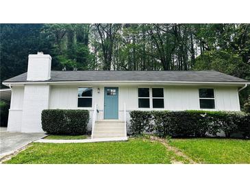 Charming single-story home with a brick chimney, white siding, and a well-manicured front lawn at 810 Commodore Nw Dr, Atlanta, GA 30318