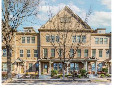 Attractive townhome featuring a symmetrical facade, covered porch, and manicured landscaping at 507 Grove Field Ct, Suwanee, GA 30024