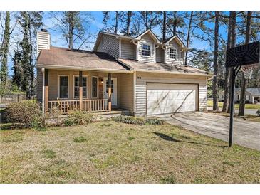 Charming home with a welcoming front porch, attached garage, and a basketball hoop in the driveway at 570 Knollwood Dr, Stockbridge, GA 30281