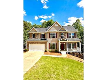 Charming two-story home with a brick and beige exterior, a two-car garage, and a welcoming front porch at 9645 Dunhill Way, Cumming, GA 30028