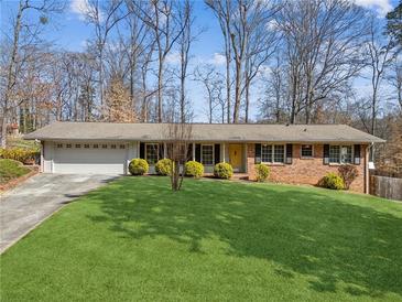Charming brick ranch home with a well-manicured lawn and a two-car garage is surrounded by mature trees at 2264 Winding Way, Tucker, GA 30084