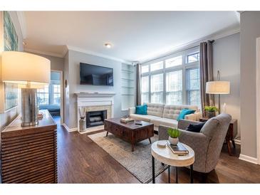 Bright living room boasts hardwood floors, large windows, a fireplace, and a contemporary design at 240 Renaissance Ne Pkwy # 112, Atlanta, GA 30308