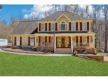 Charming two-story home featuring a welcoming front porch with elegant columns and well-manicured lawn at 215 Morning Glory Rdg, Canton, GA 30115