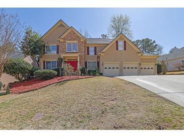 Charming two-story home featuring a three-car garage, stone accents, and a vibrant red front door at 1621 Telfair Chase Way, Lawrenceville, GA 30043