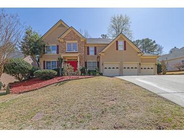 Two-story home featuring a three-car garage, red front door, and a combination of stone and siding at 1621 Telfair Chase Way, Lawrenceville, GA 30043