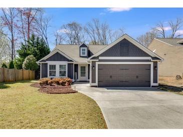 Charming home with two-car garage, dark siding, well-manicured lawn, and beautiful landscaping at 245 Raleigh Way, Villa Rica, GA 30180