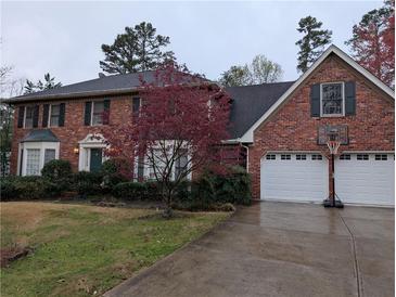 Charming brick home with a two-car garage, black shutters, a green door, and a well-manicured front yard at 3015 Ascot Ln, Roswell, GA 30076