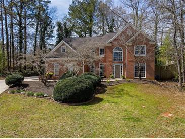 Charming brick home with a well-manicured lawn and mature trees in a serene, wooded setting at 3851 Westwick Nw Way, Kennesaw, GA 30152