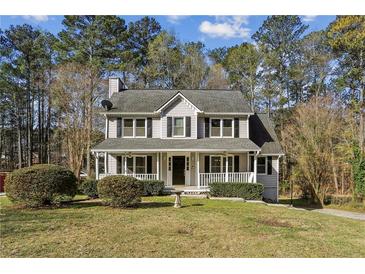 Charming two-story home featuring a welcoming front porch and well-manicured lawn surrounded by mature trees at 928 Gate Post Ln, Lawrenceville, GA 30044