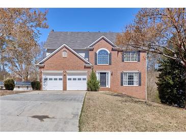 Charming two-story brick home with a two-car garage and a well-manicured front lawn on a sunny day at 1484 Highland Bluff Ct, Suwanee, GA 30024