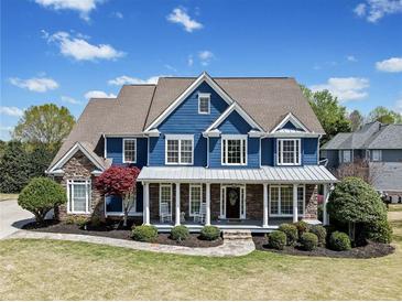 Charming two-story home featuring a welcoming front porch, manicured lawn and a combination of stone and siding at 302 Meadow Lark Xing, Canton, GA 30114