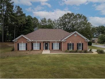Charming single-story red brick home featuring black shutters, well-manicured lawn, and mature trees at 3020 Templeton Ln, Loganville, GA 30052