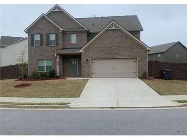 Two-story brick home with a two-car garage and well-manicured front yard on a sunny day at 212 Eleanora Way, Loganville, GA 30052