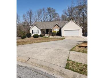 Ranch-style home with a two-car garage, driveway, and a yard with mature trees at 210 Vintage Dr, Covington, GA 30014