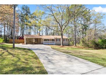 Charming single-story home with a long driveway and a covered porch, nestled among mature trees on a sunny day at 5095 Derry Nw Rd, Acworth, GA 30101