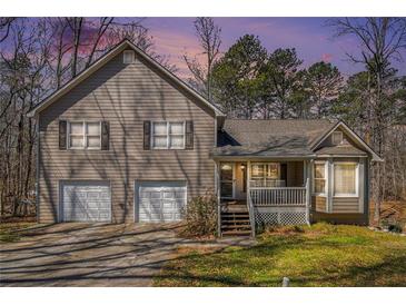 Charming two-story home with a front porch and a two-car garage and tan siding and shutters at 321 Oak Landing Cir, Douglasville, GA 30134