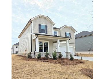 Charming two-story home featuring a welcoming front porch with stone accents and a two car garage at 2654 Mourning Dove Drive (Lot 39), Grayson, GA 30017