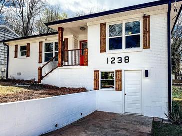 Renovated white brick home featuring contrasting wood shutters and a red front door, showcasing modern curb appeal at 1238 Westboro Sw Dr, Atlanta, GA 30310