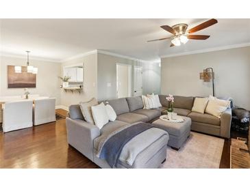 Open-concept living room boasts hardwood floors, a ceiling fan, and a comfortable gray sectional sofa at 2901 Lenox Rd # 1002, Atlanta, GA 30324