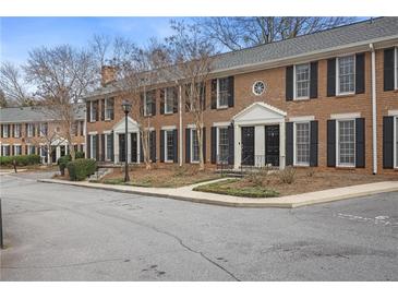 A brick townhouse with black shutters, trimmed windows, and well manicured landscaping at 1101 Collier Nw Rd # V3, Atlanta, GA 30318