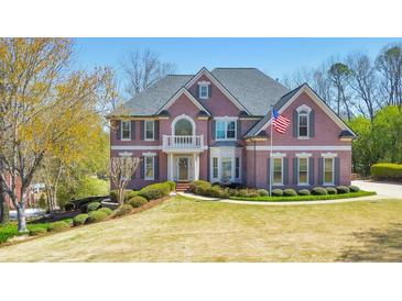 Beautiful brick home featuring a well-manicured lawn, an American flag, and mature trees at 4073 Hickory Fairway Dr, Woodstock, GA 30188