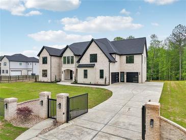 Stunning two-story brick home with black trim, arched entryway, black gated entrance, and a spacious three car garage at 1255 E M Croy Rd, Sugar Hill, GA 30518