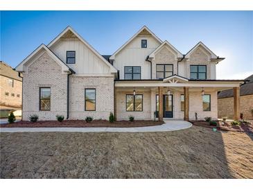 Striking two-story home boasts a brick facade, inviting porch, and well-manicured lawn at 4281 Sierra Creek Ct, Hoschton, GA 30548