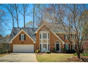 Charming two-story brick home featuring a manicured lawn and attached two-car garage at 210 Chiswick Close, Johns Creek, GA 30022
