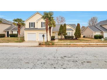 Inviting two-story home featuring a well-maintained lawn, palm trees, and a two-car garage at 4410 Millenium View Ct, Snellville, GA 30039